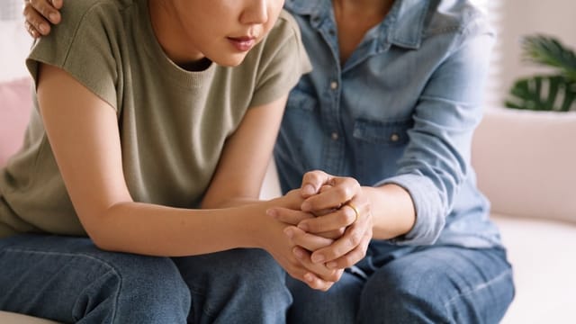 Woman with her hands grasped speaking to her mother.
