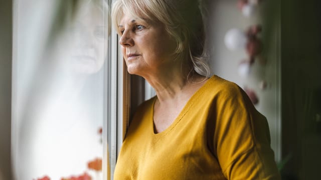 Older woman, grandmother age, pensive and staring out window