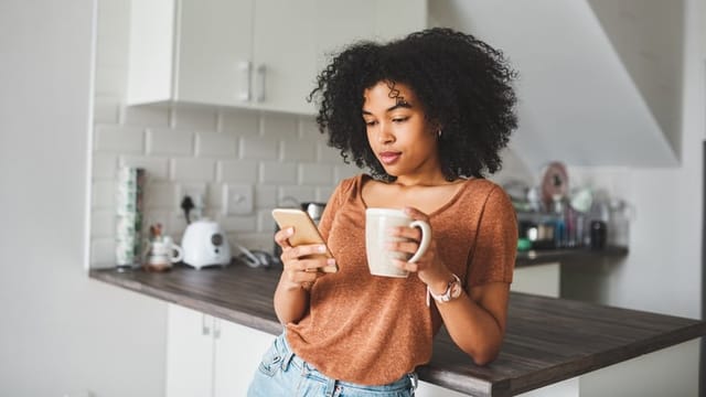 woman texting in kitchen