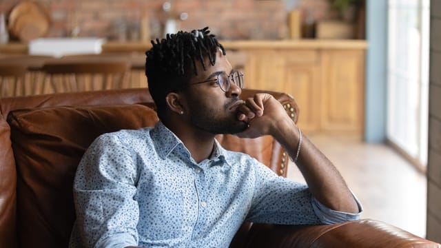 thoughtful millennial guy on couch