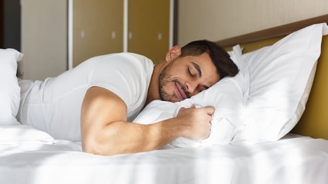 Young man peacefully sleeping in his bed.