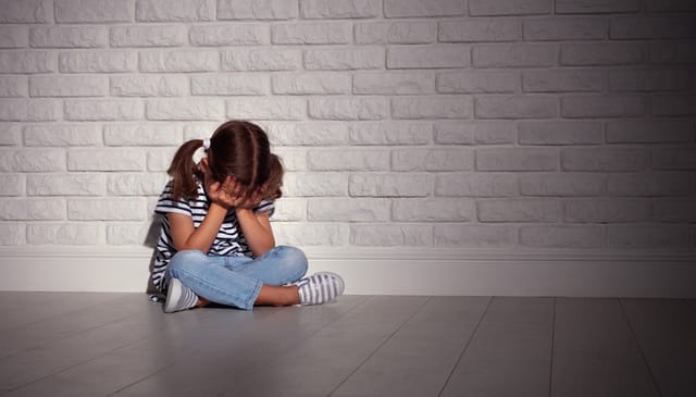 upset sad sad child girl in stress cries at an empty dark wall