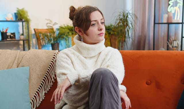 serious woman sitting cross-legged on couch