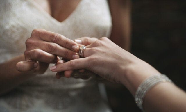 woman placing ring on bride's finger