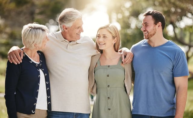 Happy loving caucasian family with adult children standing together in nature on a sunny day. Happy senior couple posing outdoors with their daughter and son in law