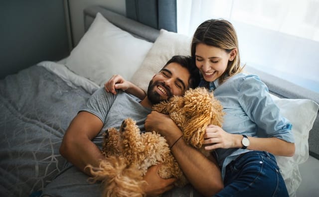 couple cuddling with dog in bed