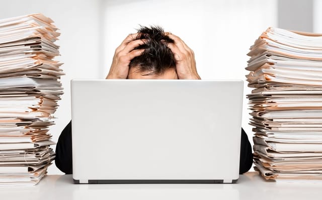 Man with work piled up at his desk.