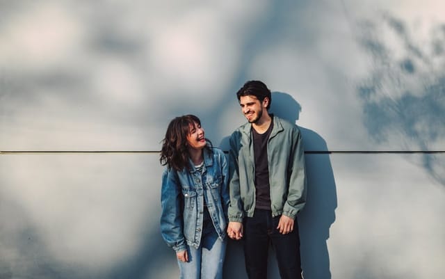 couple in denim standing against wall