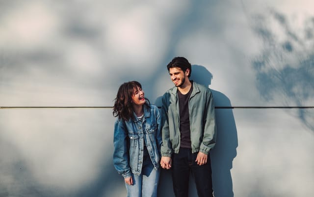 couple in denim standing against wall