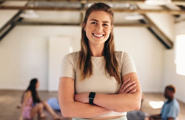smiling woman with arms crossed yoga studio