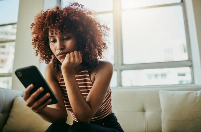 sad woman texting on couch