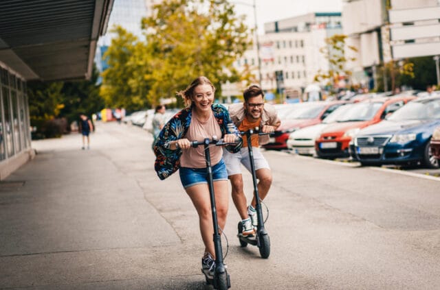 couple riding scooters in city