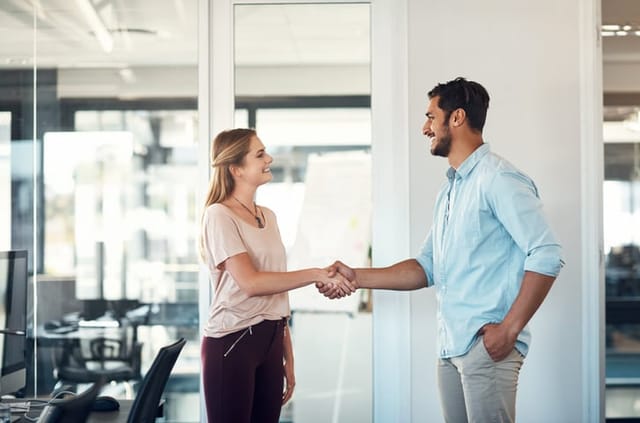 man and woman shaking hands in office