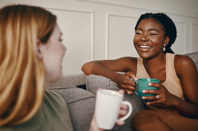 two friends chatting on the couch with tea