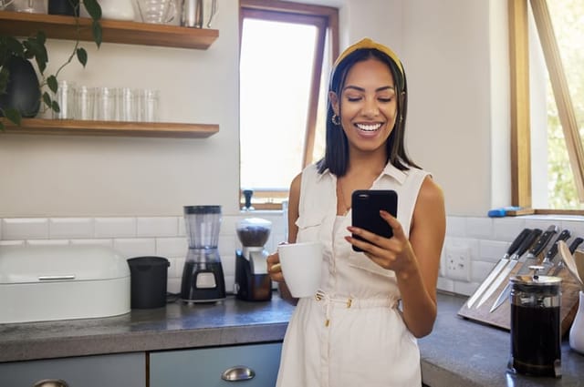 smiling woman with coffee on smartphone