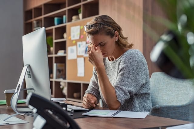 woman with head in hands at desk stressed out