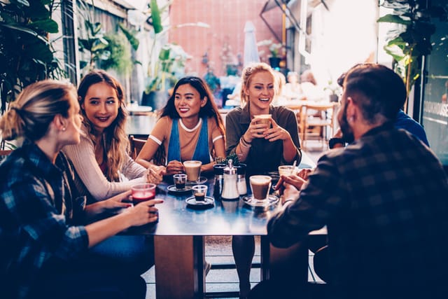 Multi-ethnic friends relaxing, talking and having fun at modern urban hipster coffee shop