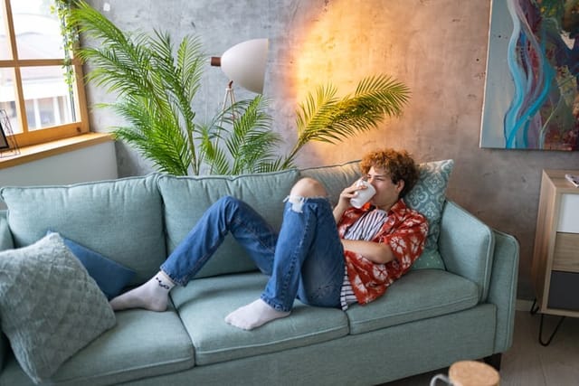 hipster guy drinking tea on couch