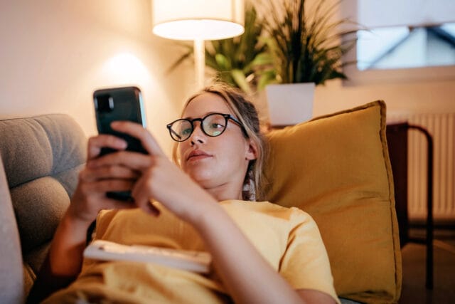 woman lying on couch texting