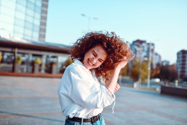smiling curly-haired redhead woman outdoors