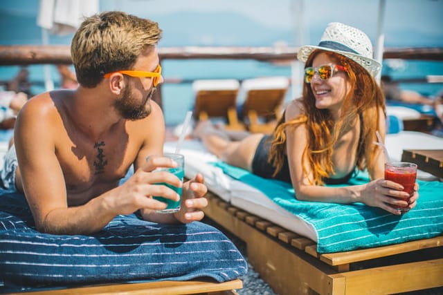 couple having drinks on beach loungers