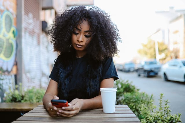 sad woman texting outdoors at coffee shop