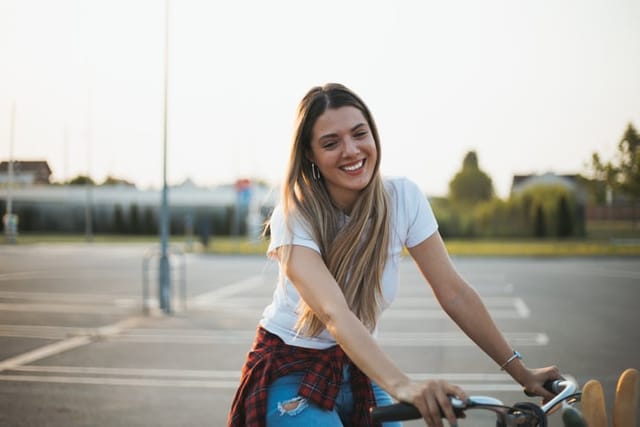 smiling woman riding bike parking lot