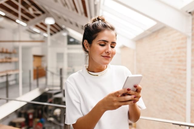 smiling brunette millennial woman texting