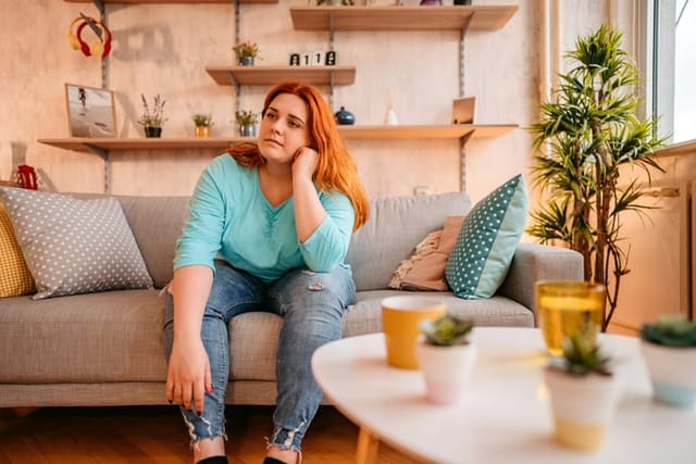 sad redhead woman sitting on couch