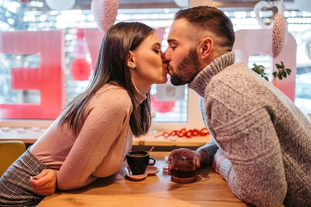 couple kissing over cafe table