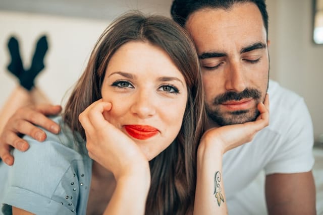 woman smiling with boyfriend's chin in her palm