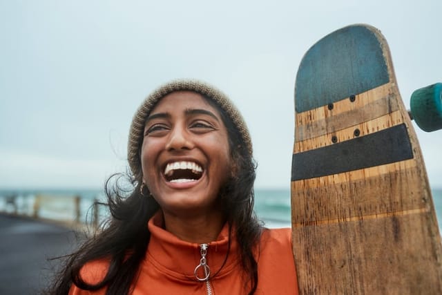 smiling woman on beach with longboard