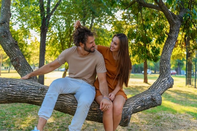 couple sitting on tree branch in park