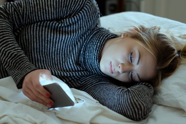 blonde woman texting in bed