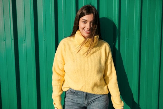 smiling woman yellow sweater green background