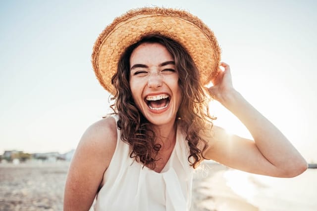 smiling woman with hat on beach