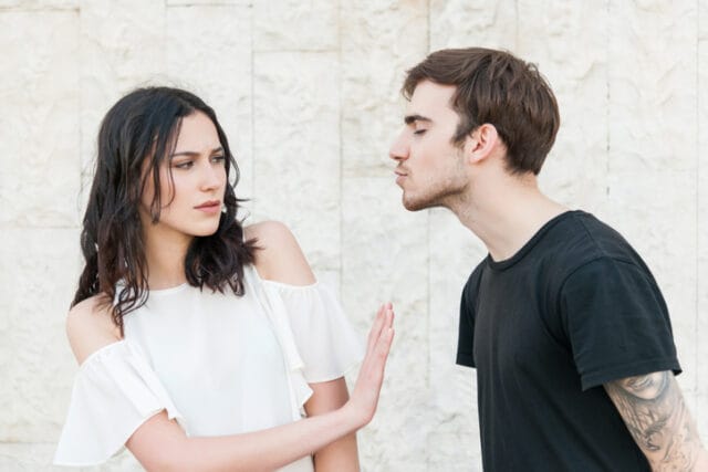 woman rejecting man's kiss