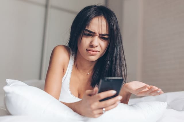 annoyed woman texting in bed