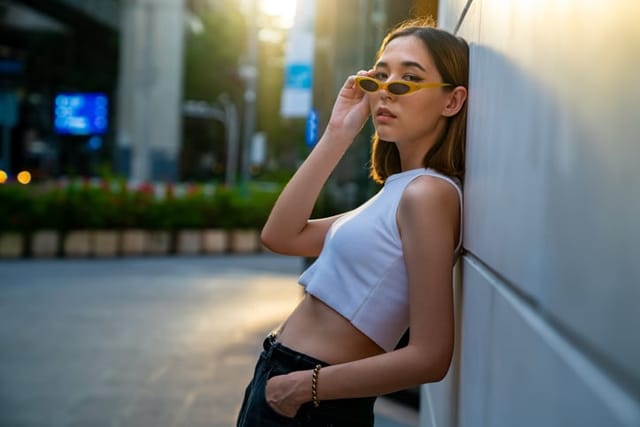 woman with sunglasses leaning against wall