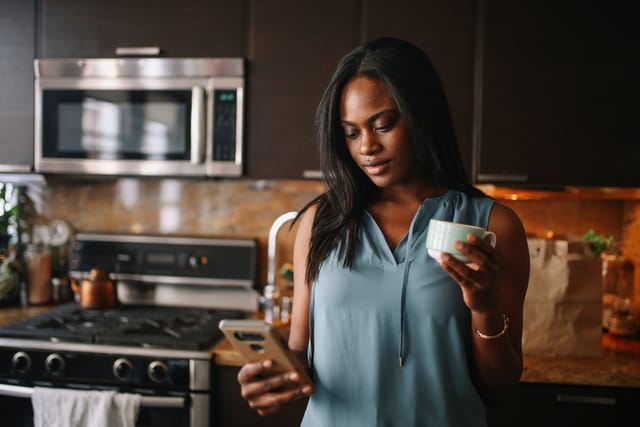 woman texting in kitchen