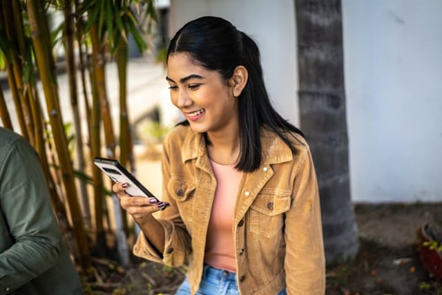 woman smiling texting outdoors