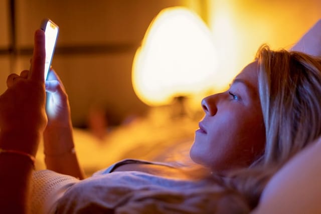woman texting laying in bed