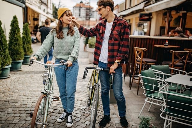 hipster couple walking bikes through city