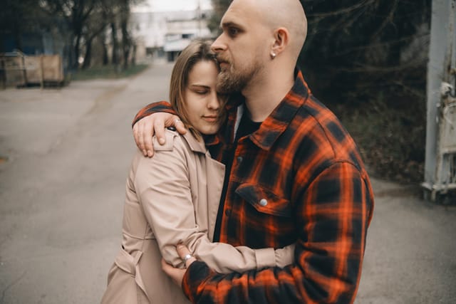 woman embracing serious boyfriend outside