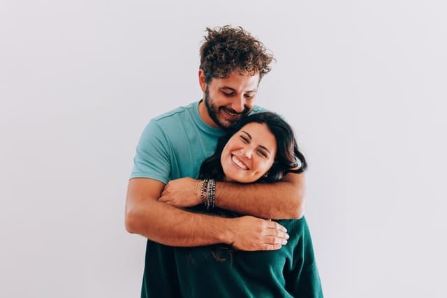 happy woman being hugged from behind by boyfriend