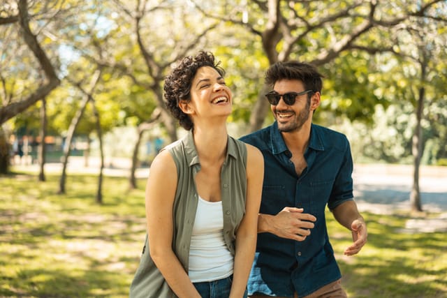 couple laughing while walking in park