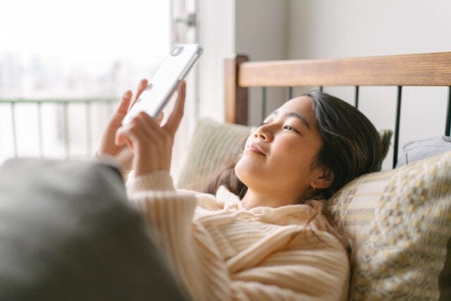 smiling woman texting in bed