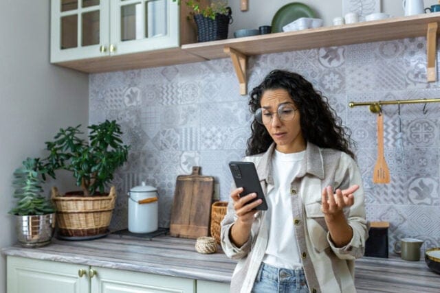 confused woman texting in kitchen