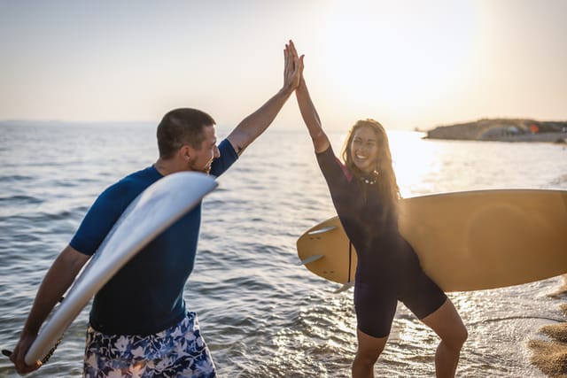 surfing couple giving high fives