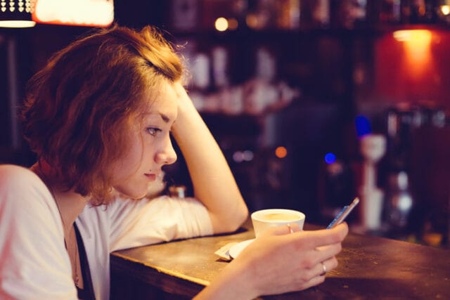 sad woman texting at bar alone